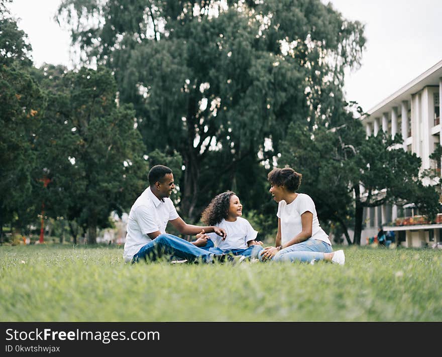 Family Sitting on Grass Near Building