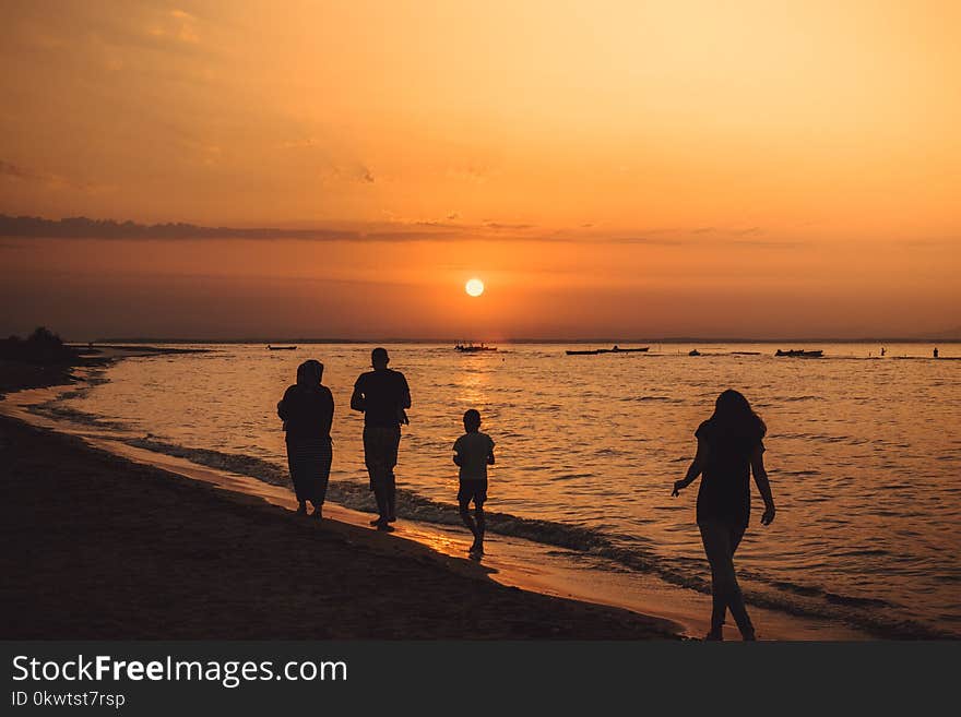 Silhouette Of People Walking On Seashore During Sunset