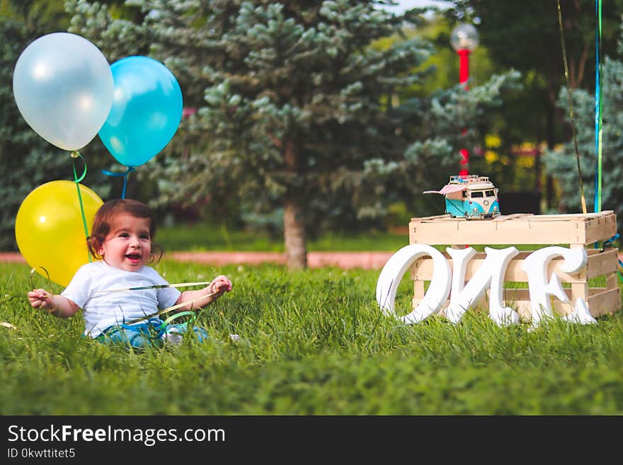 Girl Holding Blue and Yellow Balloons