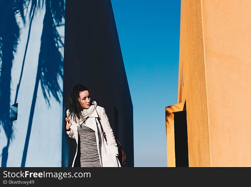 Woman in White Coat Leaning on Wall