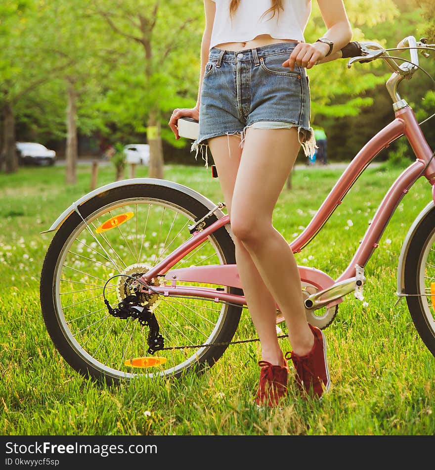 Beautiful woman with bicycle on the meadow in the park. Closeup picture. Beautiful woman with bicycle on the meadow in the park. Closeup picture