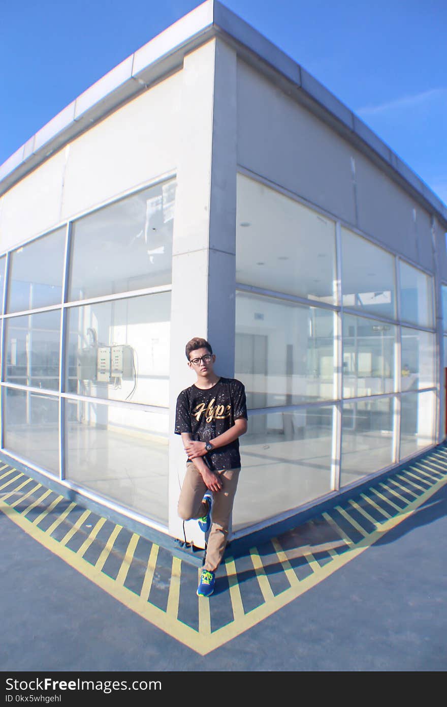 Man Leaning on Corner of Building With Glass Walls