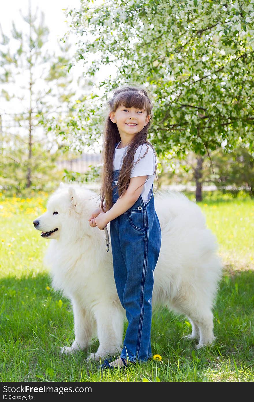 A beautiful 5 year old girl in jeans hugs her favorite dog during a summer walk. A beautiful 5 year old girl in jeans hugs her favorite dog during a summer walk.