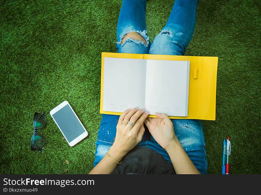 Girl,woman looking at the book and smartphone sitting in park.