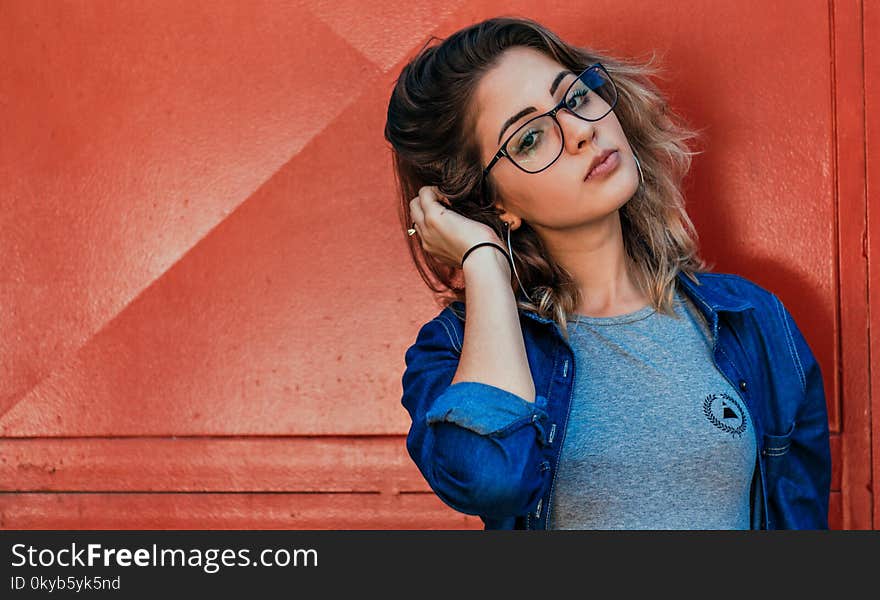 Closeup Photo of Woman Holding Her Hair Leaning on Red Wall