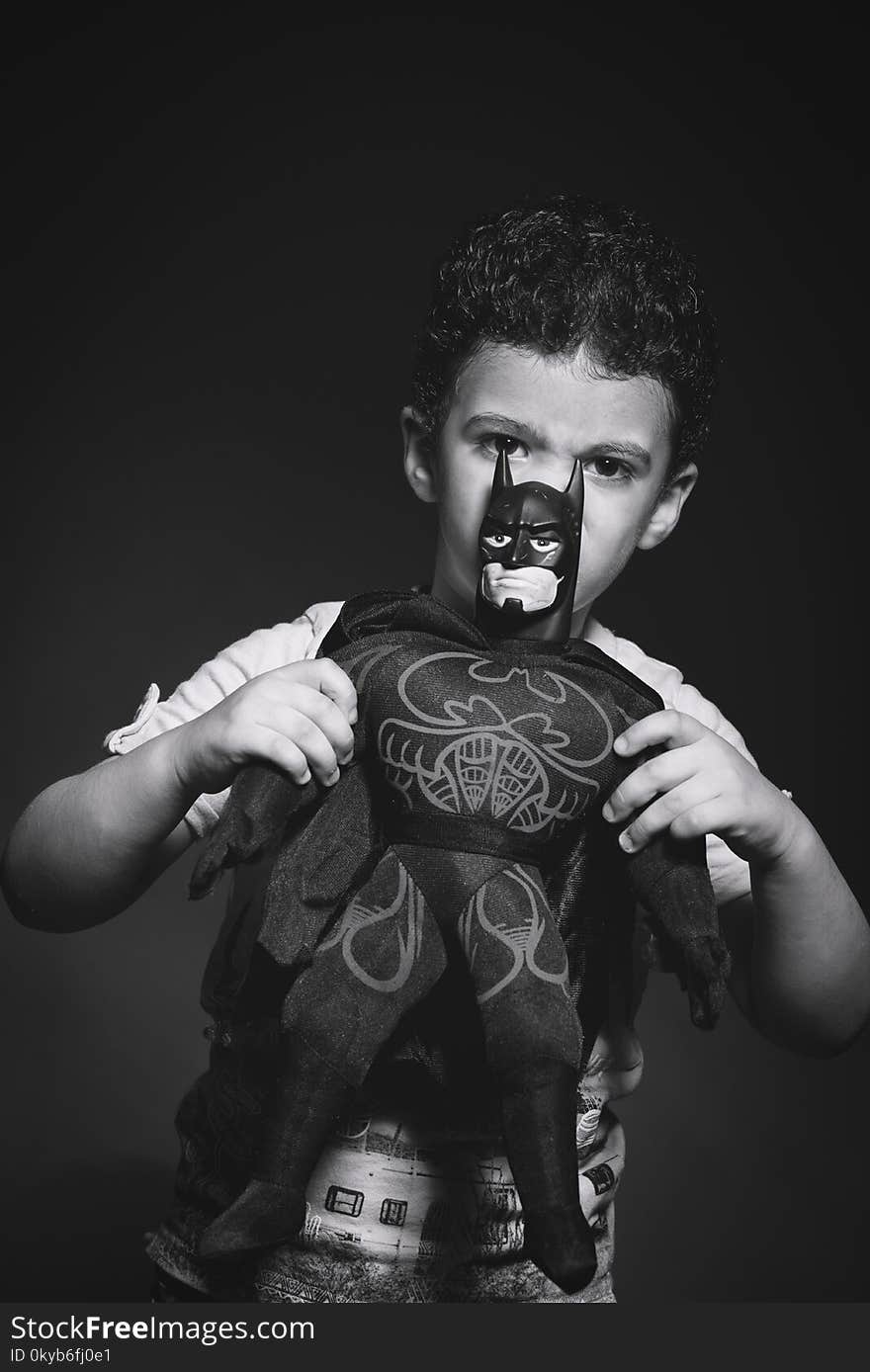 Grayscale Photo of Boy Holding Batman Plush Toy