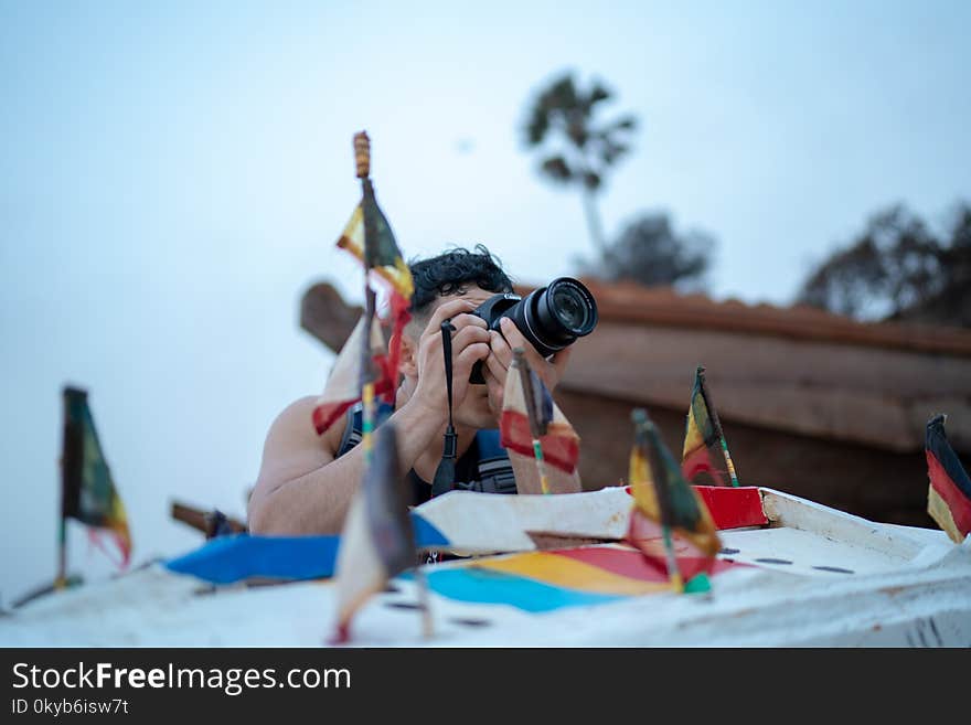 Man Taking Photo Using Dslr Camera Near Country Flag Miniatures