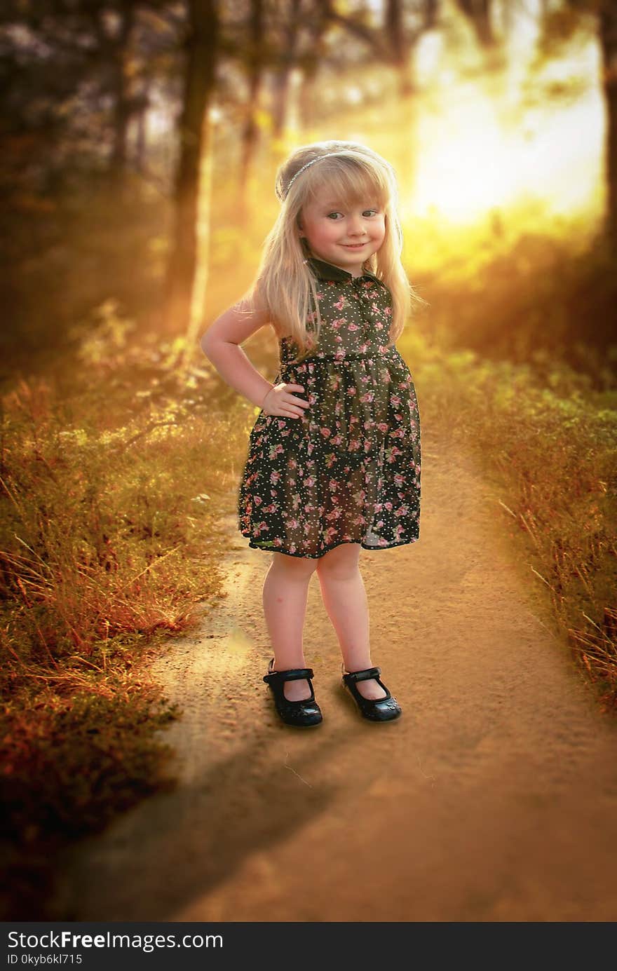 Girl in Black and Pink Floral Sleeveless Dress Stands in Pathway