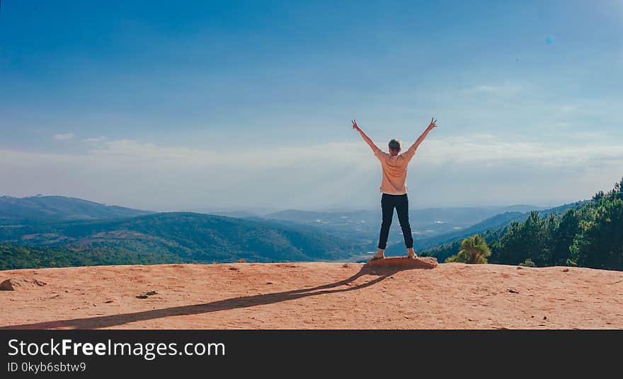 Person in Beige Top on Mountain Cliff