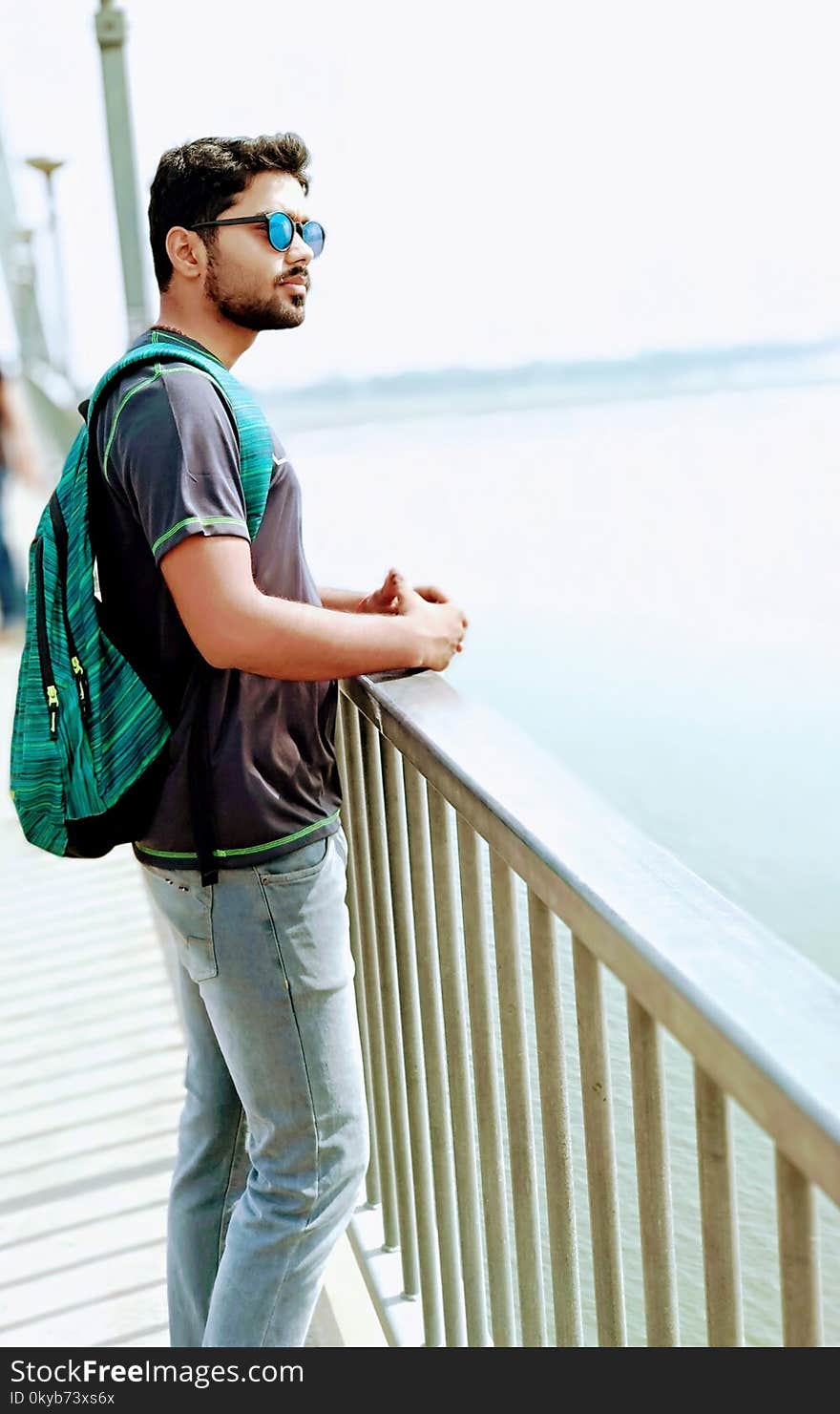 Man Wearing Black Shirt and Blue Denim Jeans Standing on Dock