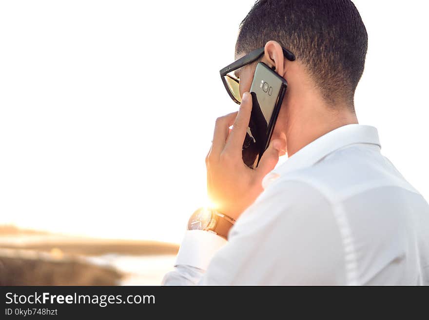 Shallow Focus Photography of a Man in White Collared Dress Shirt Talking to the Phone Using Black Android Smartphone