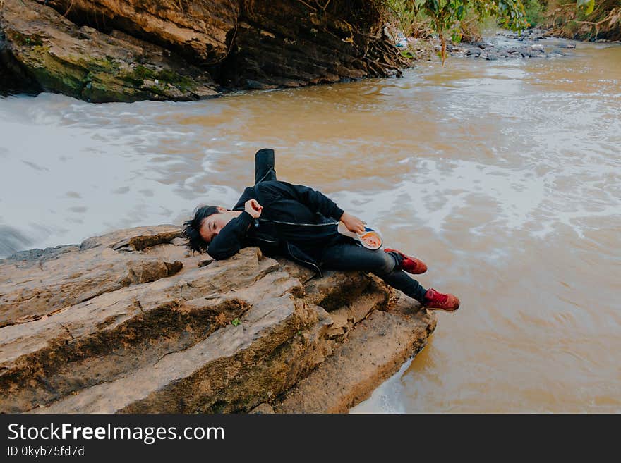 Photo of Man Lying on Rock at River