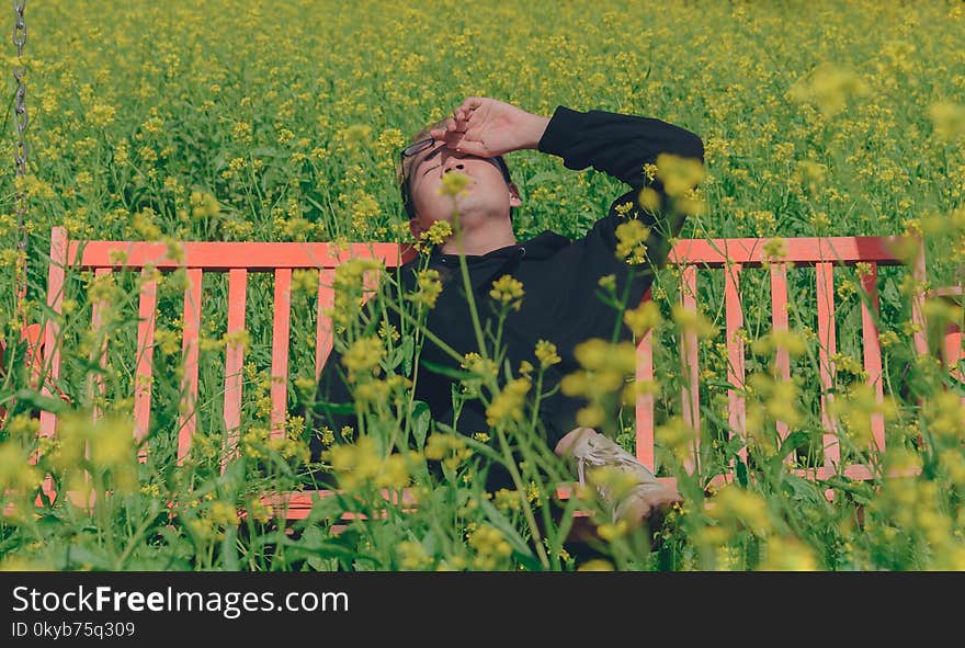 Man in Black Hoodie Sitting on Red Bench