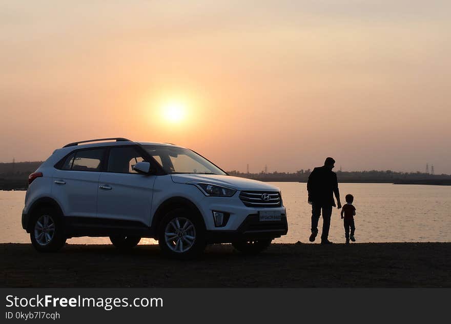 Silhouette of Man and Child Near White Hyundai Tucson Suv during Golden Hour