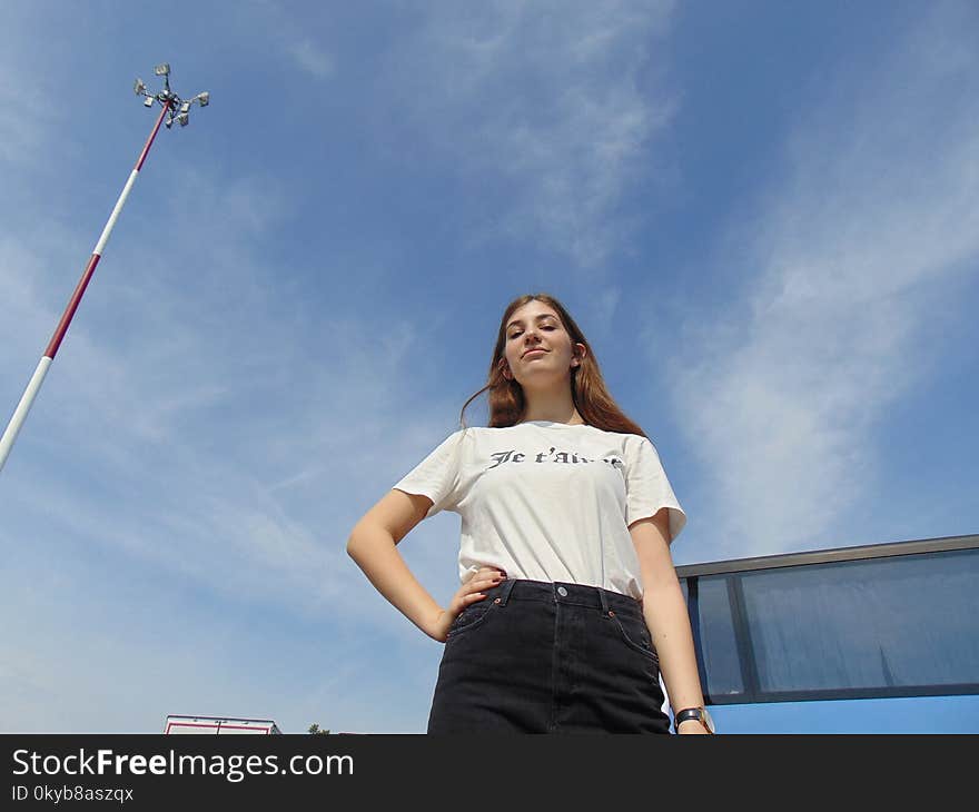 Woman Wears White Shirt and Black Denim Bottoms Stand Near Antenna