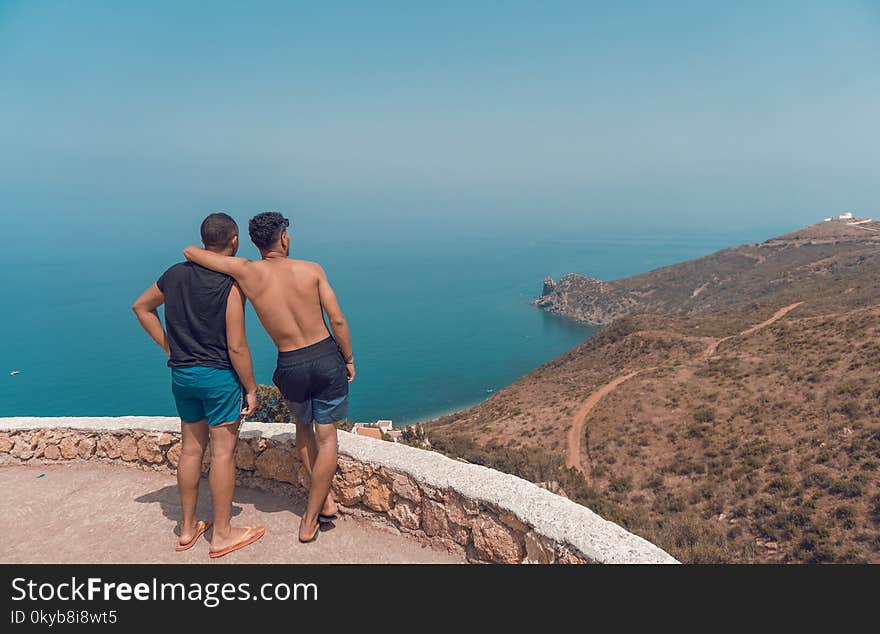 Two Man Standing on Mountain Cliff With Ocean View