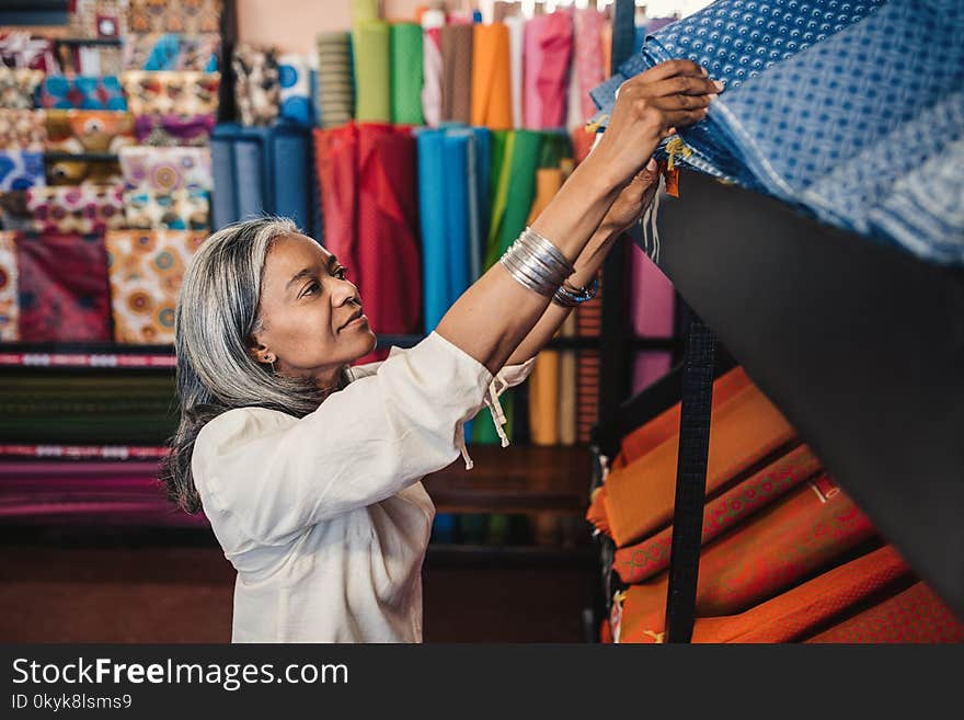 Mature woman looking through cloth rolls in a fabric shop