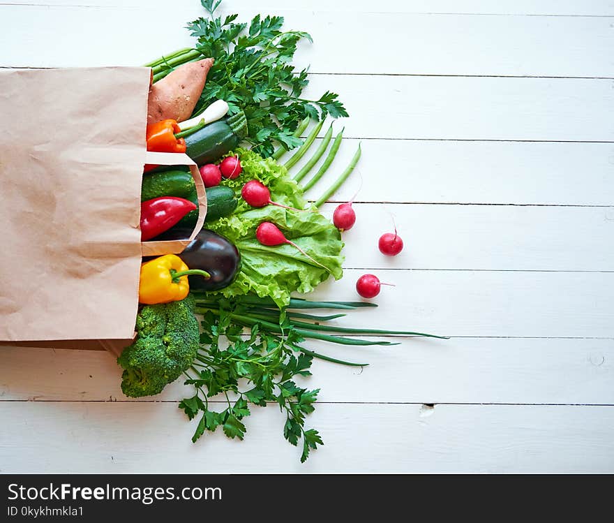 Fresh organic vegetables on white wooden boards background, top view.