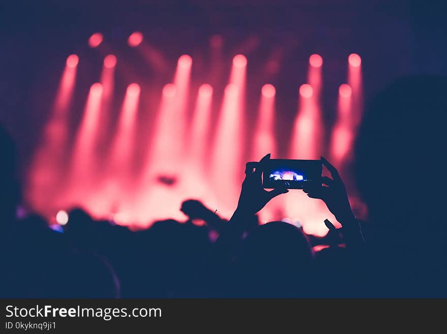 Image of hands using camera phone to take pictures and videos at live concert. Image of hands using camera phone to take pictures and videos at live concert