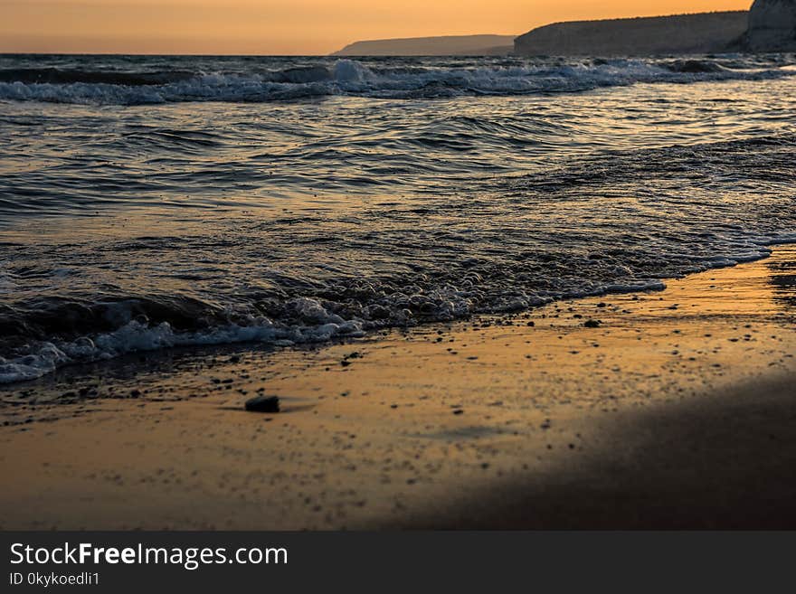 Waves approaching sandy beach during the sunset