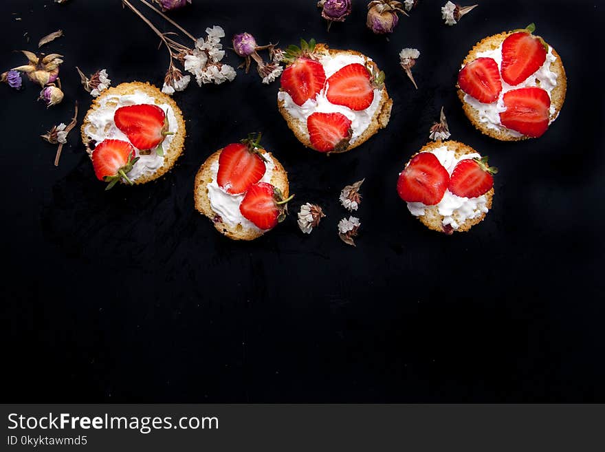 Fluffy buttermilk biscuits shortcake with red ripe strawberries and fresh whipped cream on a black background. Horizontal image. Copy space