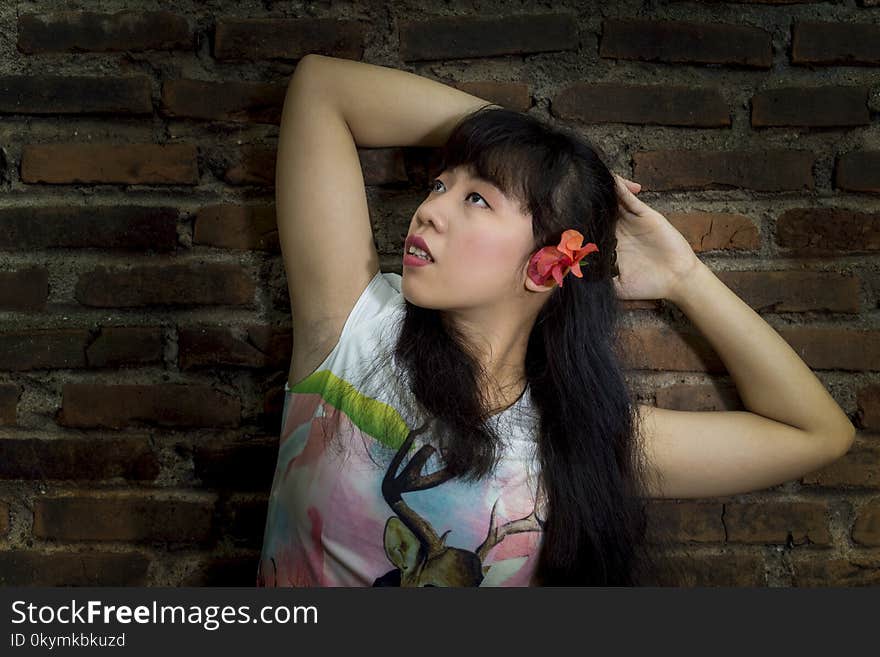 Asian young girl standing by an old brick wall