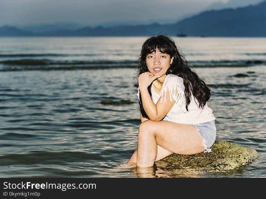 Girl sitting on a rock in the evening sea. Girl sitting on a rock in the evening sea