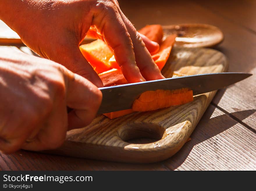 Slicing cooking carrots on wooden cutting board. Slicing cooking carrots on wooden cutting board