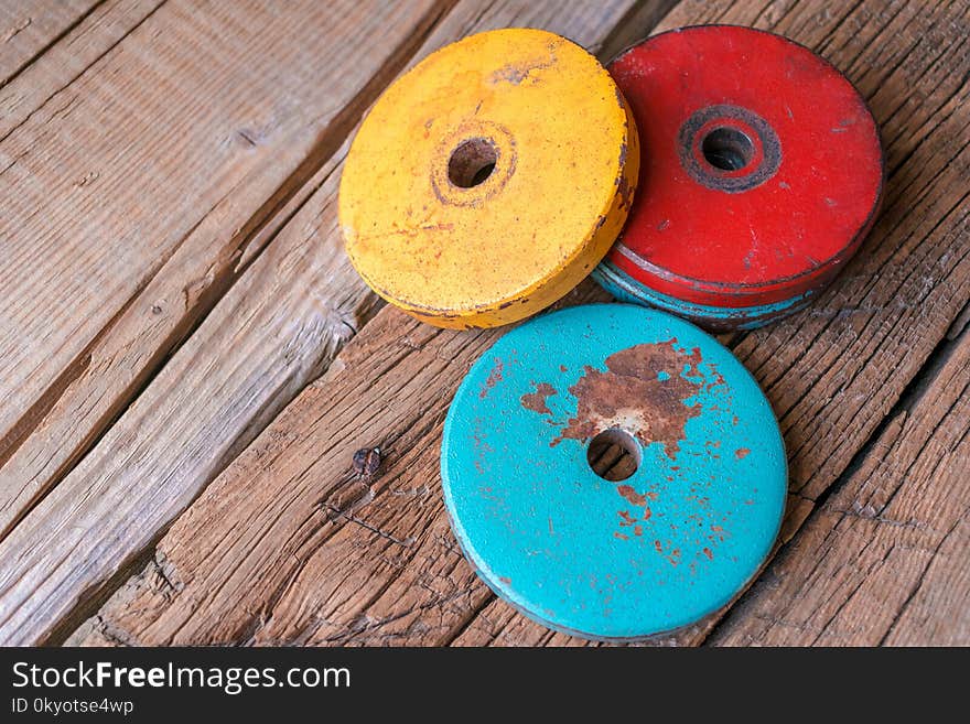 Photo of colored old pancakes for dumbbells. On a wooden background. Photo of colored old pancakes for dumbbells. On a wooden background.