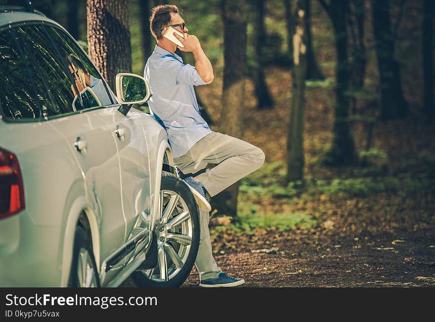 Caucasian Men in His 30s Making Cellphone Conversation Inside the Forest. Office Worker Taking Short Break From His Work. Caucasian Men in His 30s Making Cellphone Conversation Inside the Forest. Office Worker Taking Short Break From His Work.