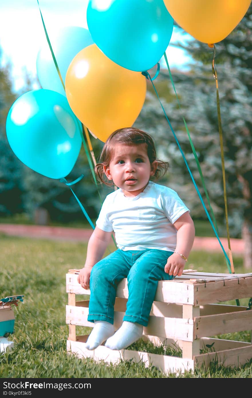 Girl Wearing White Shirt And Blue Jeans Sitting On Wooden Crate