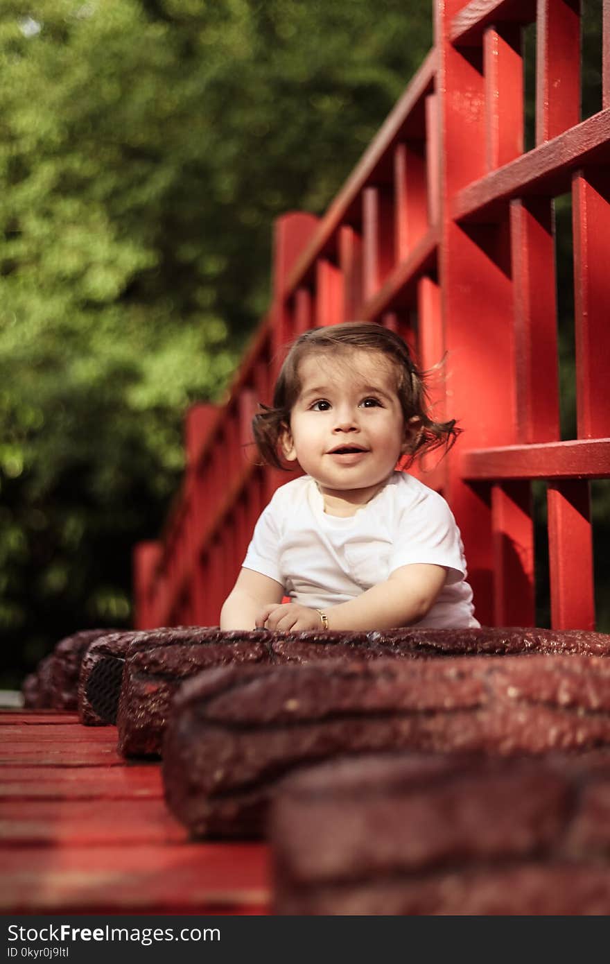 Baby Wearing White Crew-neck Shirt Beside Red Wooden Fence