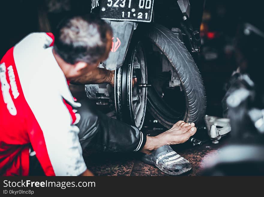 Man Changing a Rear Tire of a Motor Scooter