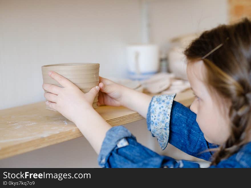 Child hobby. creative pottery leisure. artistic kid upbringing. little girl putting a handmade clay jug on a shelf. Child hobby. creative pottery leisure. artistic kid upbringing. little girl putting a handmade clay jug on a shelf