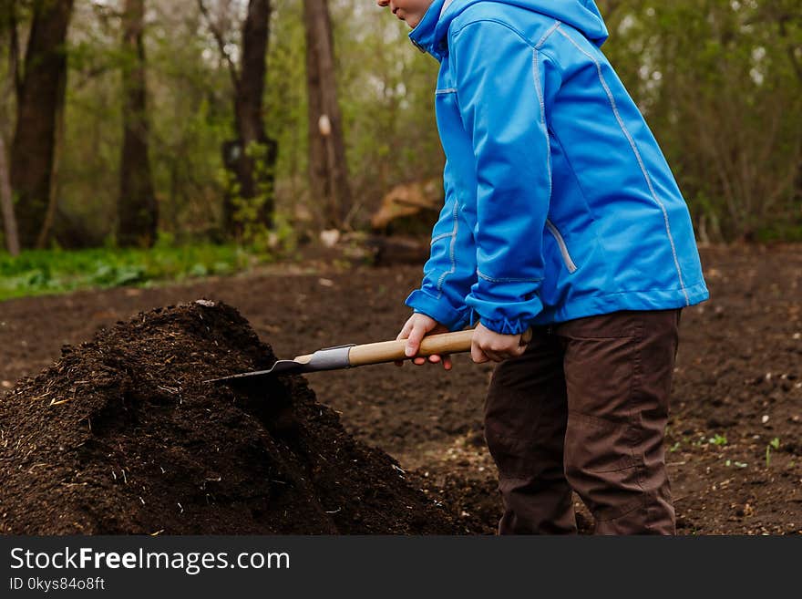 The child is gaining ground shovel in the garden. The child is gaining ground shovel in the garden