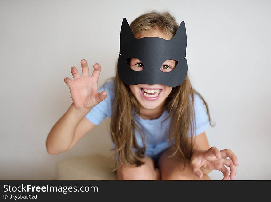 The girl plays in a self-made mask of black cat for Halloween