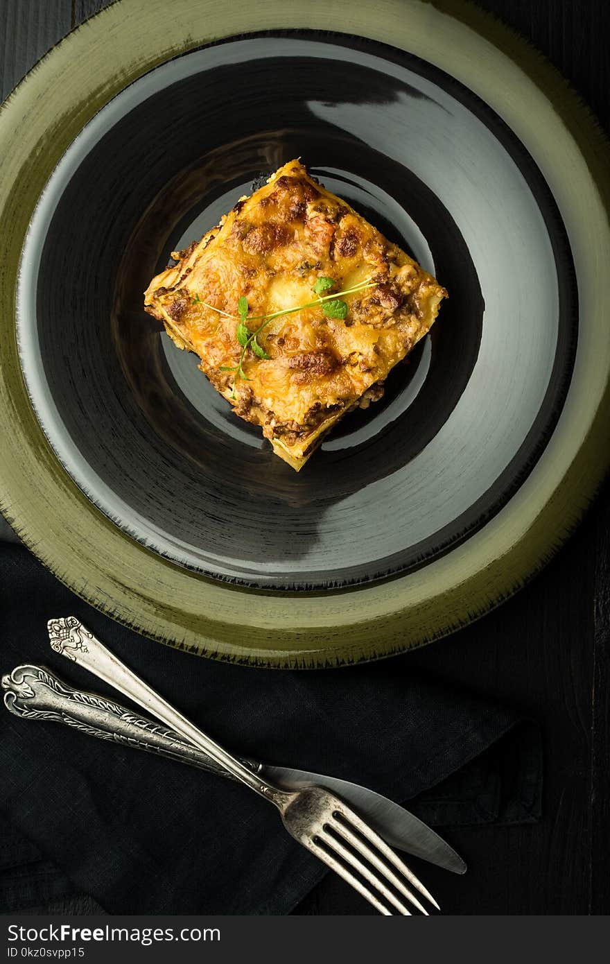 Traditional Lasagna With Minced Beef, Bolognese Sauce and Basil on Dark Plate. Italian Cuisine.