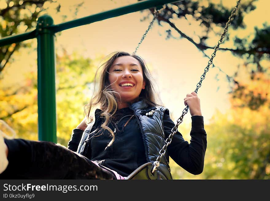 The girl of the eastern appearance laughs and swings on a swing