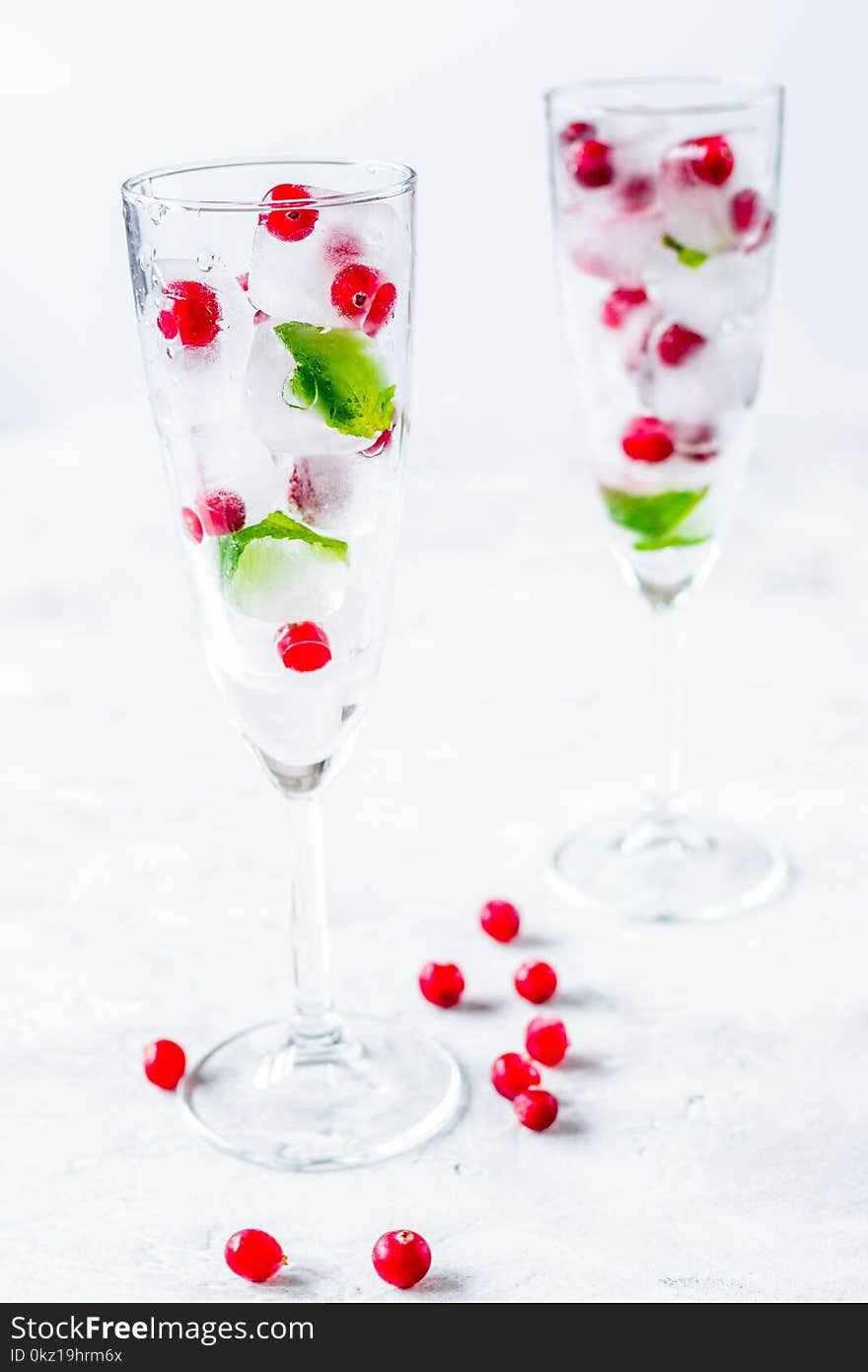 Ice cubes with fresh berries and mint in glasses for summer drink on white table background. Ice cubes with fresh berries and mint in glasses for summer drink on white table background