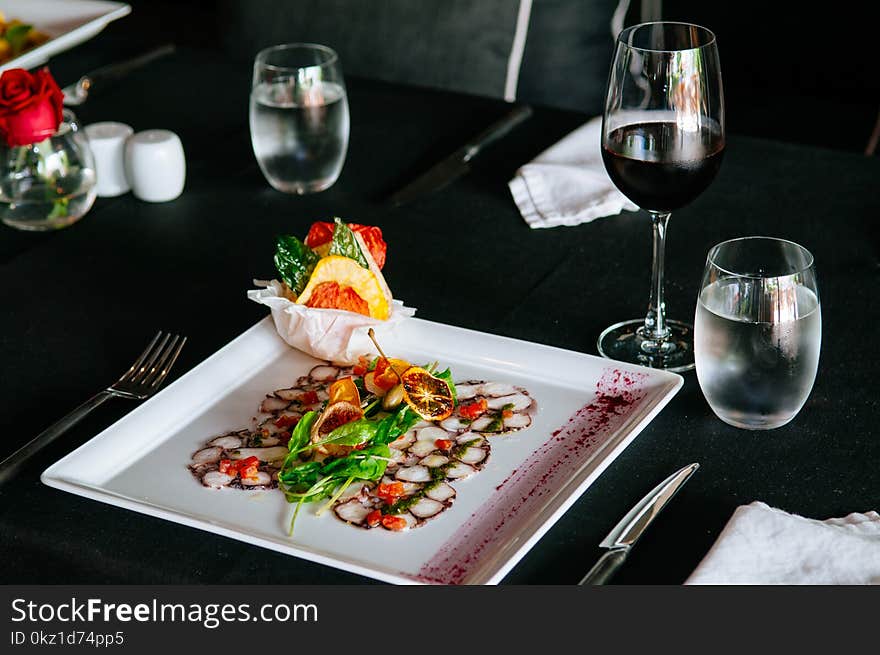 Fresh octopus carpacio with citrus spinach salad pesto balsamic dressing, fine dinning table setting