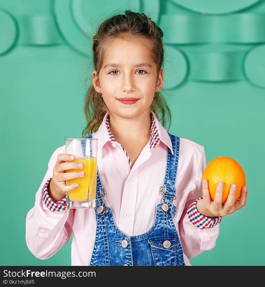 Kid girl drinks orange juice for breakfast. Square. The concept of a healthy lifestyle, food, childhood, vitamins, vegetarianism.