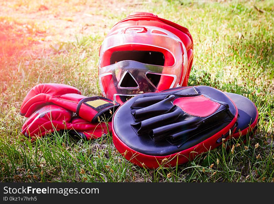 A protective helmet, gloves and Boxing paws lie on the grass. A protective helmet, gloves and Boxing paws lie on the grass