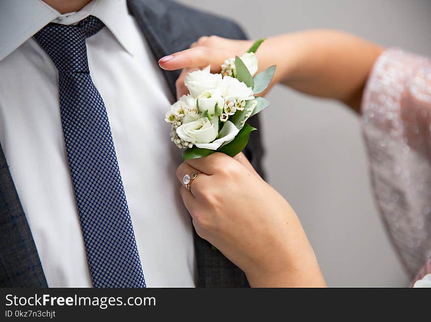 Bride fastens groom boutonniere to buttonhole