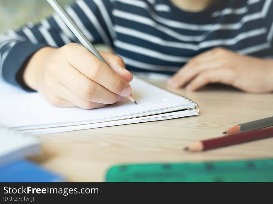 Kid holding pencil and writing in notebook. Close up. Kid holding pencil and writing in notebook. Close up.