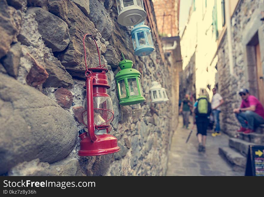 Colorful petroleum lamps hanging from a wall in narrow street.