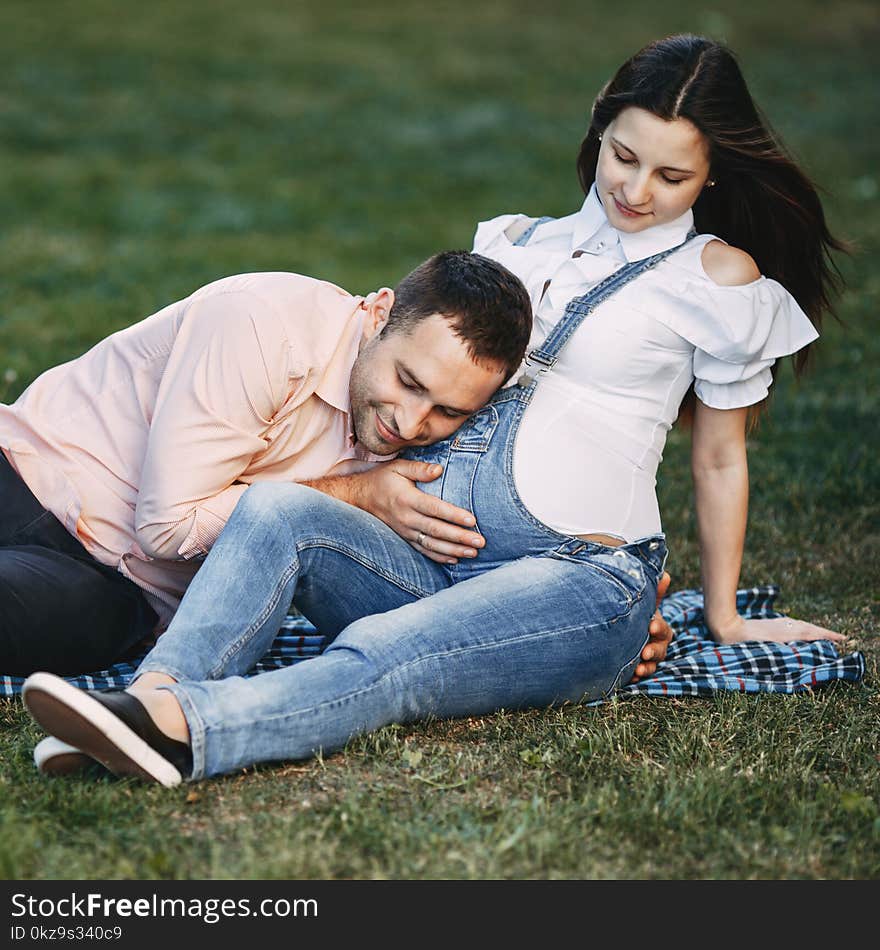 Father-to-be listening to baby moving inside belly. Pregnant couple hugging in nature. Happiness, love, family concept. Father-to-be listening to baby moving inside belly. Pregnant couple hugging in nature. Happiness, love, family concept