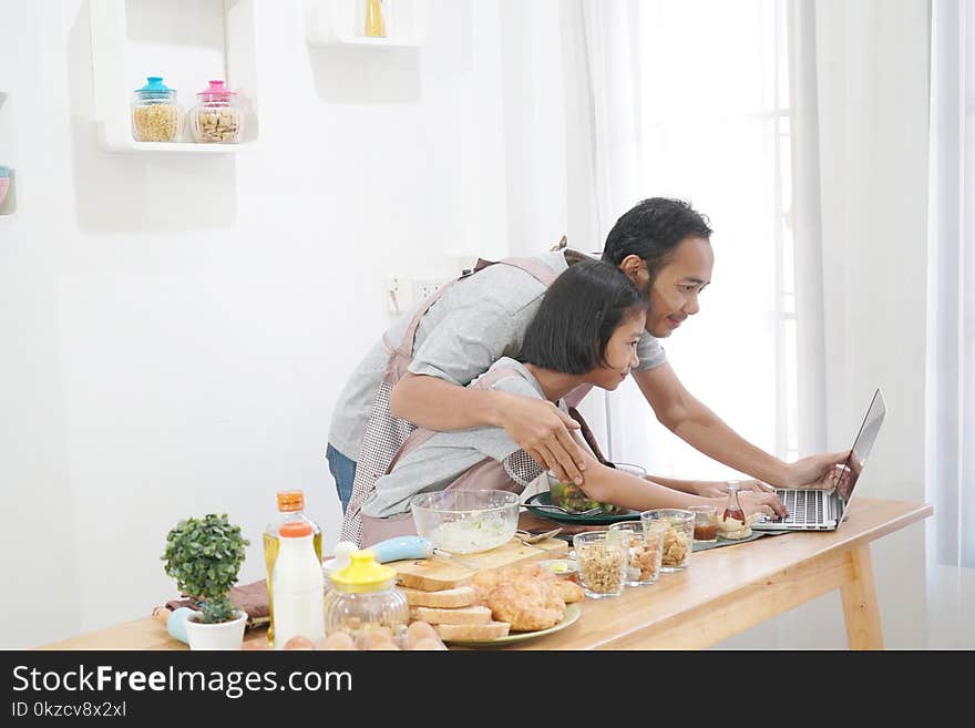 Father and daughter learning online cooking using laptop computer