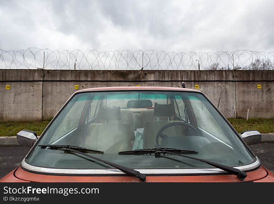 Closeup Photo of Red Car Near Concrete Wall