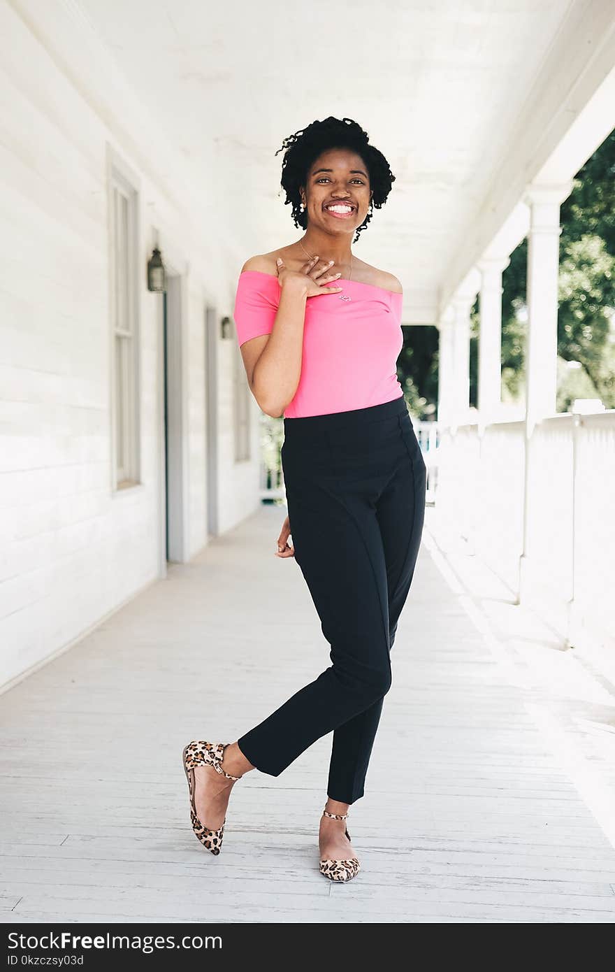 Woman Wearing Pink Off-shoulder Shirt and Black Pants While Standing Near Wall