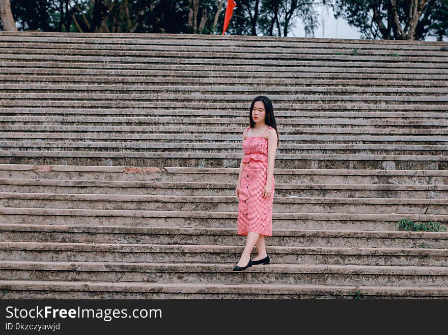 Woman Wearing Pink Spaghetti-strap Dress Standing on Grey Concrete Stairs